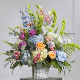 Colorful mixed flower arrangement in a white wicker basket