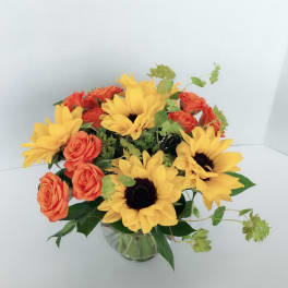 Bouquet of yellow sunflowers and orange roses in a glass vase