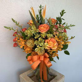 Orange and yellow mixed bouquet in a glass vase with a ribbon
