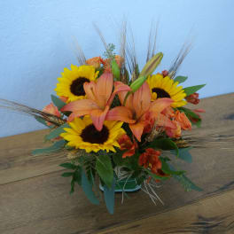 Orange lilies and yellow sunflowers in a low vase arrangement