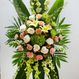Large standing floral spray with white lilies, roses, and peach carnations