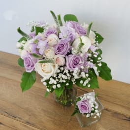 Lavender and white rose bouquet in a glass vase with a matching boutonniere