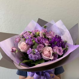 Bouquet of pink and purple roses wrapped in lavender paper