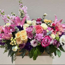 Large mixed bouquet of pink, purple, and white flowers in a container