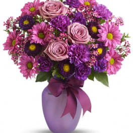 Purple and pink bouquet in a lavender vase with a ribbon