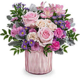 Pink and purple mixed flower arrangement with roses and carnations in a pink glass vase