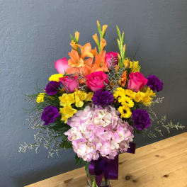 Colorful mixed bouquet in a glass vase with pink hydrangea and orange gladiolus