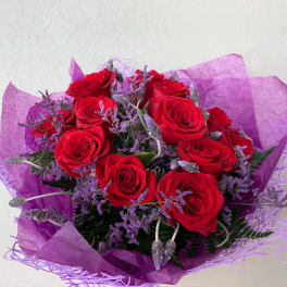 Bouquet of red roses with purple filler flowers wrapped in purple paper