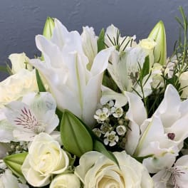 White roses and lilies in a bouquet with green buds