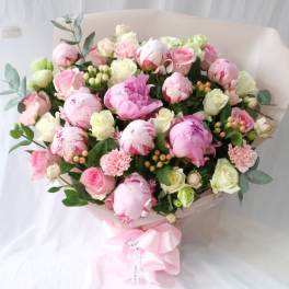 Bouquet of pink and white peonies and roses with a pink ribbon