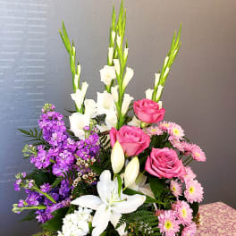 Mixed bouquet with pink roses, white lilies, and purple flowers in a basket