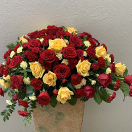 Large bouquet of red and yellow roses with red carnations in a vase