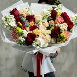 Handheld bouquet of red, cream, and pink roses wrapped in white paper