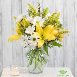 Yellow lilies and white daisies in a glass vase
