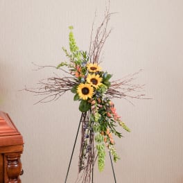 Tall floral standing spray with sunflowers and trailing greenery on a stand