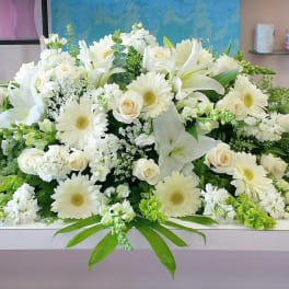 Large white floral arrangement with lilies, roses, and daisies on a table