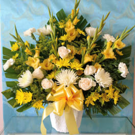 Yellow and white floral arrangement in a white vase with a yellow ribbon