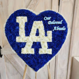 Heart-shaped floral tribute with blue and white flowers reading "LA" and "Our Beloved Abuelo"