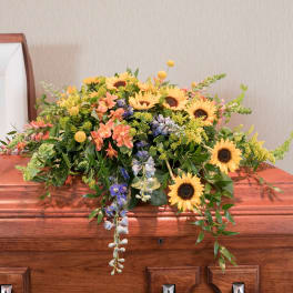 Colorful floral casket spray with sunflowers and mixed blooms