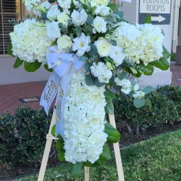 White funeral standing spray on an easel with a ribbon