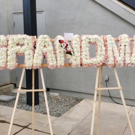 Floral sign spelling "GRANDMA" on easels with white and pink flowers
