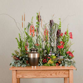 Tall floral arrangement with red and orange blooms in a bronze urn