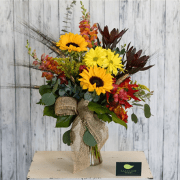 Bright sunflower bouquet with red and orange accents in a glass vase
