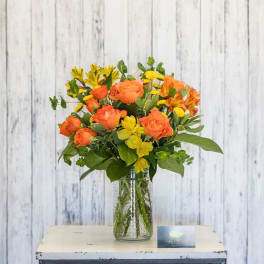 Orange and yellow flowers arranged in a clear glass vase