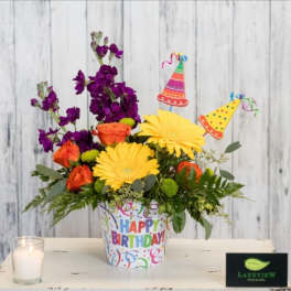 Birthday flower arrangement in a decorated pot with party picks