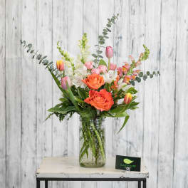 Mixed bouquet in a glass jar vase with pink, orange, and white flowers
