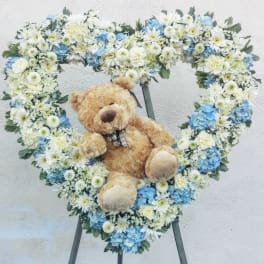 Heart-shaped floral wreath with a teddy bear in the center