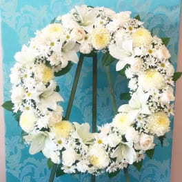 White floral wreath on a stand against a blue patterned background