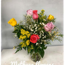 Mixed roses and small filler flowers arranged in a clear glass vase