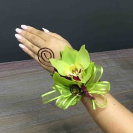 Green orchid wrist corsage with ribbon and wire accents