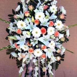 Standing floral spray with white lilies, daisies, and peach roses