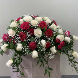 Arrangement of red and white roses with baby's breath in a fabric-covered container