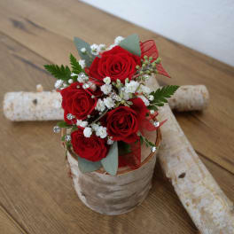 Small bouquet of red roses with white filler flowers in a rustic container