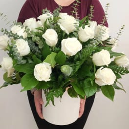 White roses in a white hatbox with eucalyptus and greenery