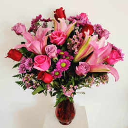 Pink and red mixed flower bouquet in a red glass vase