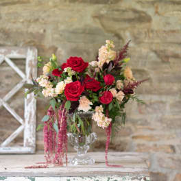 Red roses and blush flowers arranged in a clear glass vase