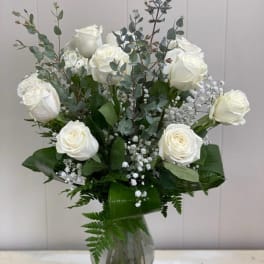 White roses and baby's breath in a clear glass vase