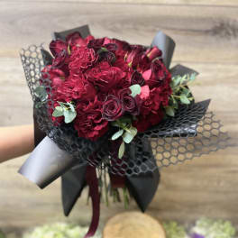 Bouquet of deep red roses wrapped in black paper