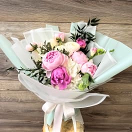 Bouquet of pink and white peonies wrapped in pastel paper