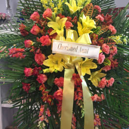 Large floral standing spray with yellow lilies and pink-orange flowers
