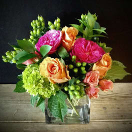 Colorful bouquet of roses and hydrangea in a clear square vase