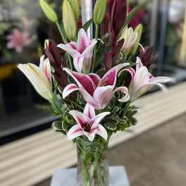Bouquet of pink and white lilies in a clear glass vase