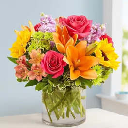 Mixed bouquet of roses, lilies, and daisies in a glass vase