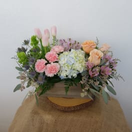 Mixed bouquet with pink tulips, roses, hydrangea, and carnations in a wooden box