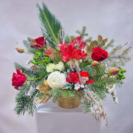 Holiday floral arrangement with red and white blooms in a gold container