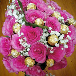 Bouquet of pink roses with white baby's breath and gold-wrapped chocolates
